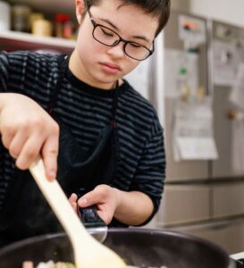 male teenager with down syndrome cooking independently