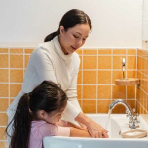 mom teaching daughter how to wash hands
